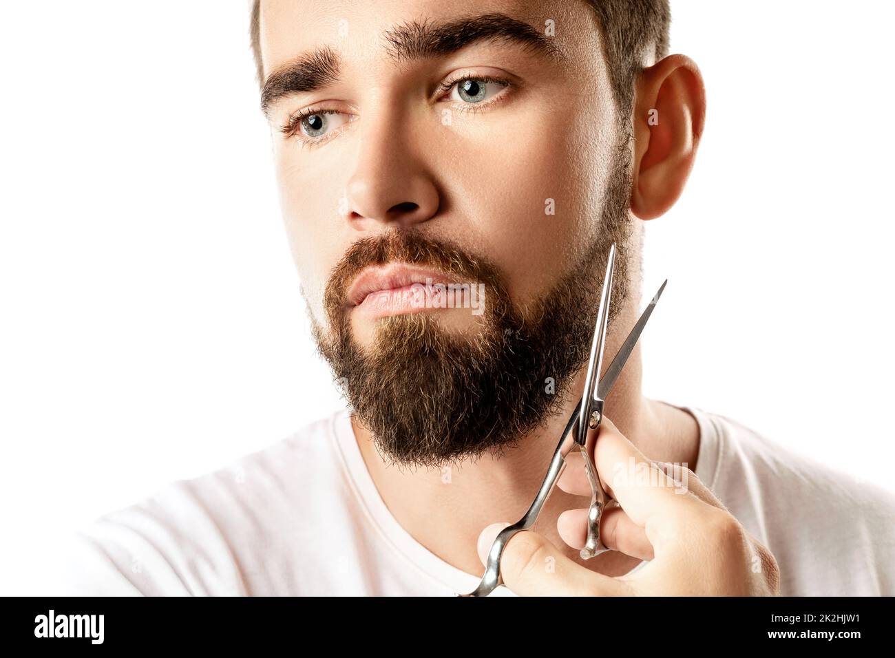 Handsome man trimming his beard with a scissors Stock Photo
