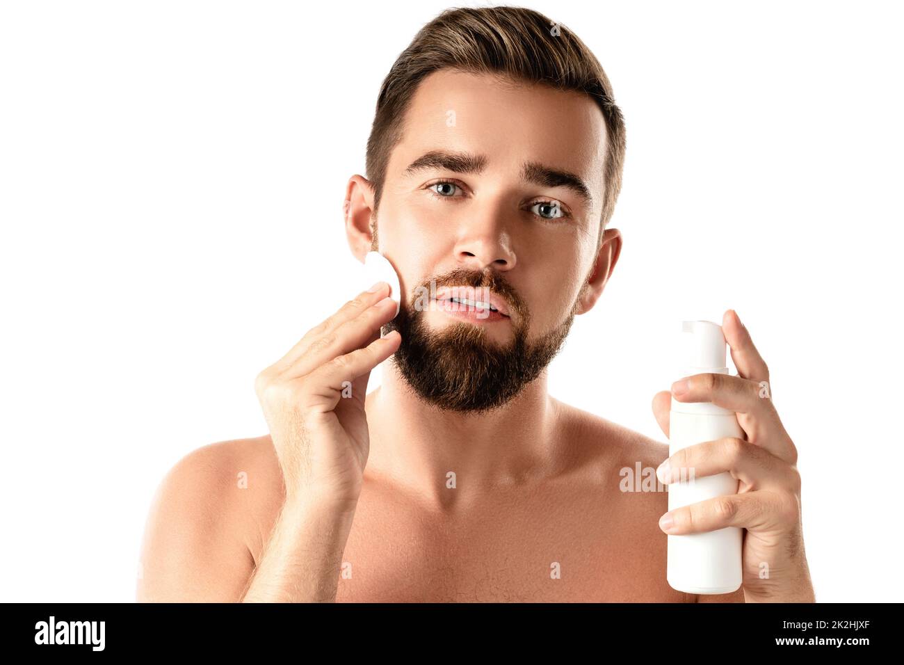 Young handsome man is cleaning his face with a cotton pad Stock Photo