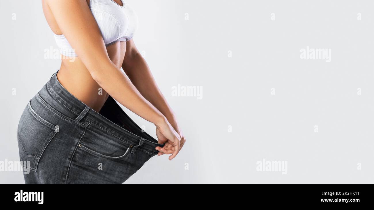 Woman showing result after weight loss wearing on old jeans Stock Photo