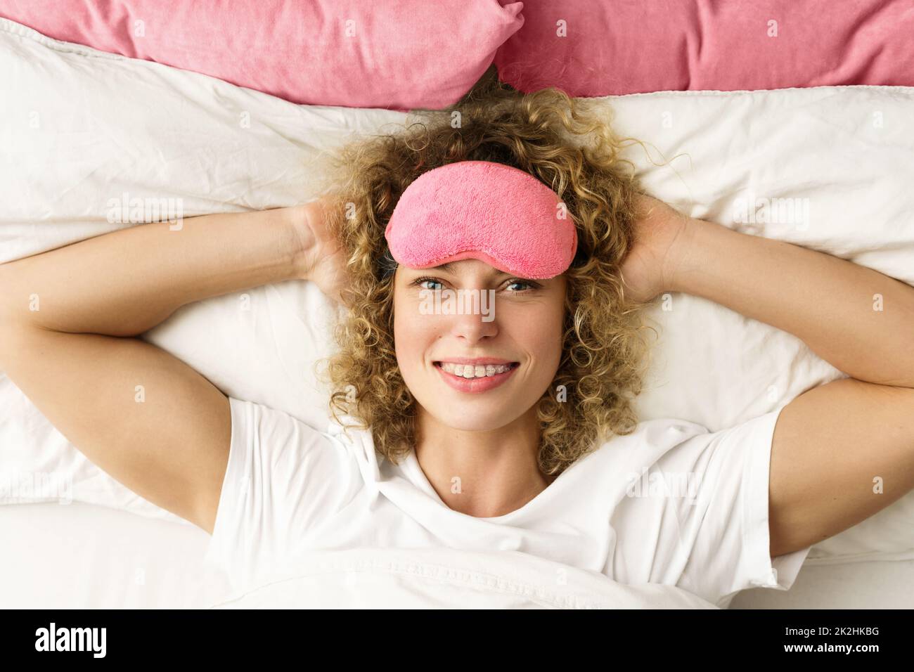 Beautiful woman with curly hair waking up after good sleep Stock Photo
