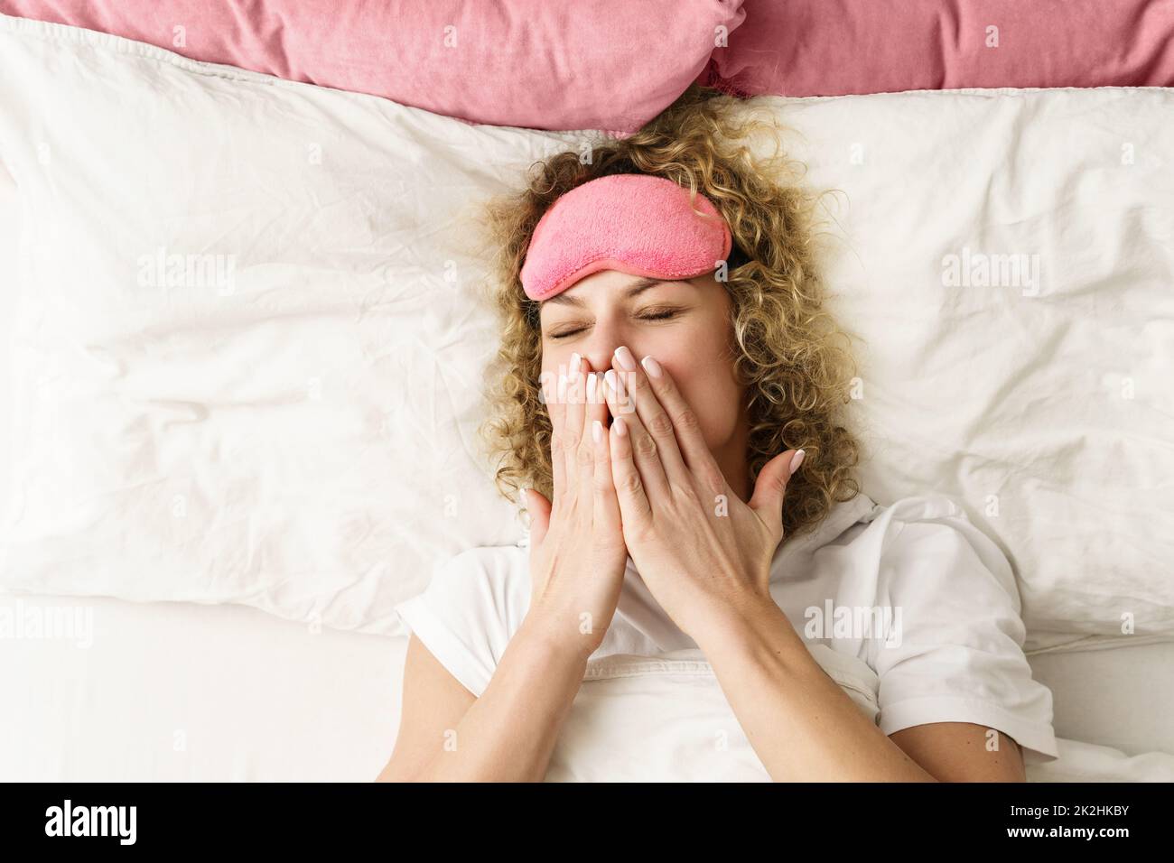 Beautiful woman with curly hair waking up after good sleep Stock Photo