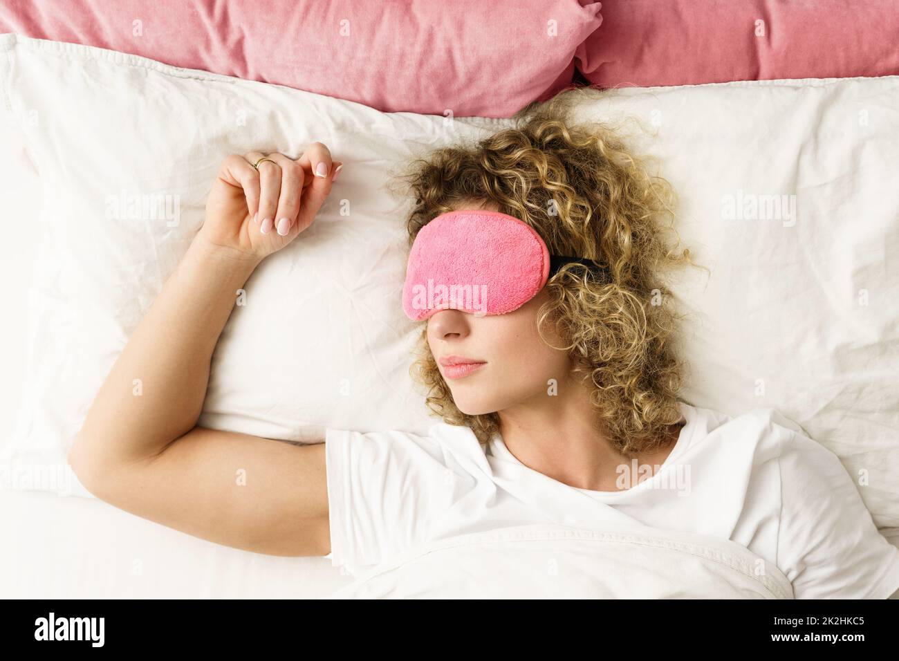 Beautiful woman sleeping with a pink blindfold on her eyes Stock Photo