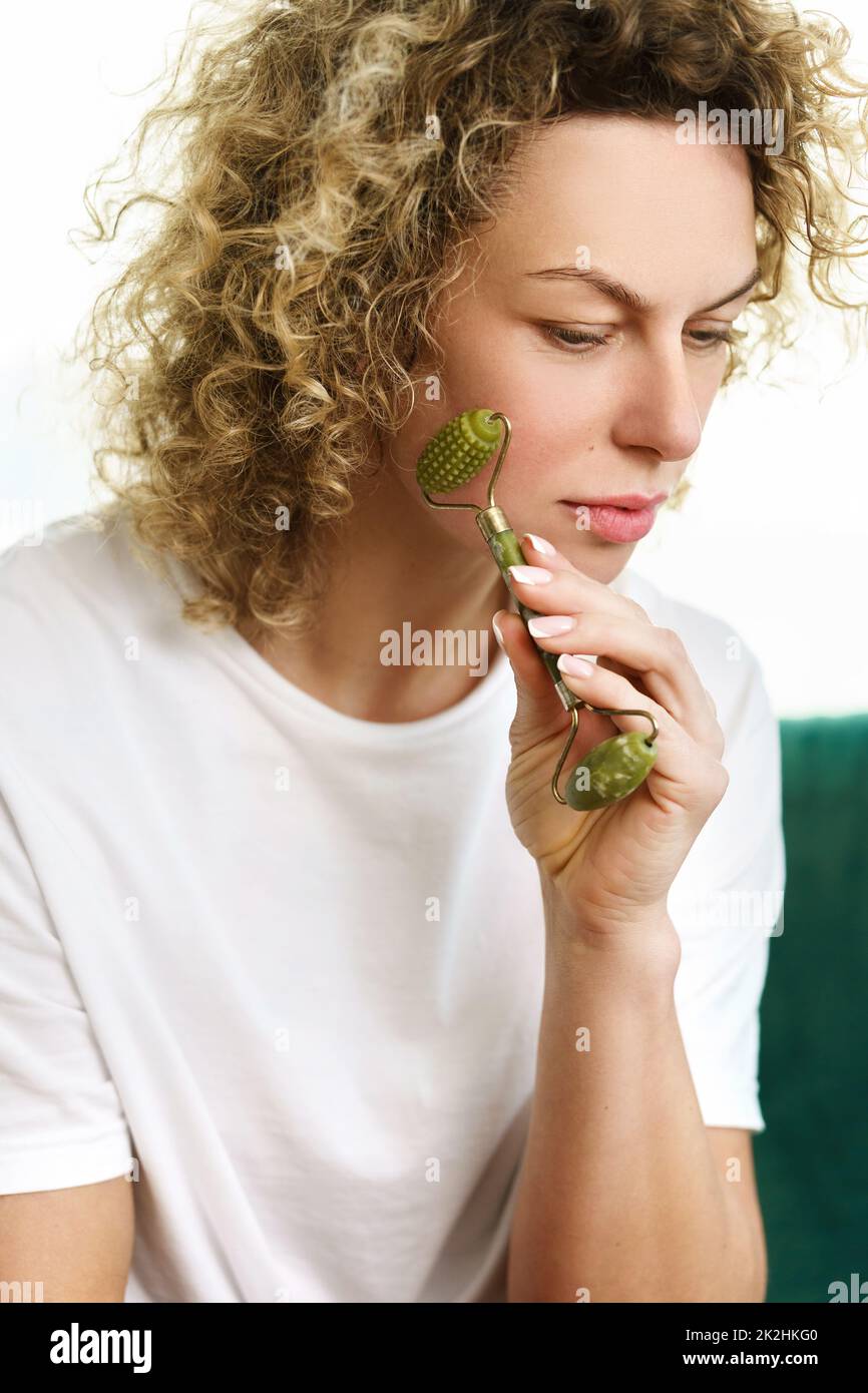 Beautiful woman making facial massage with a jade dermaroller at home Stock Photo
