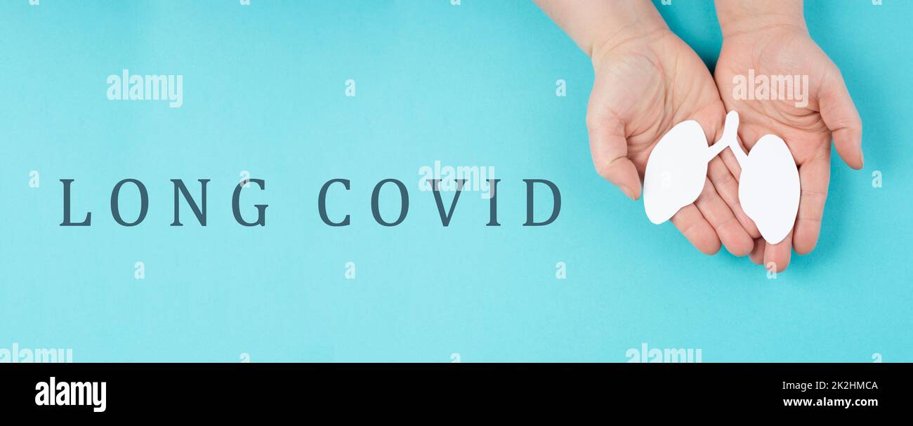 The words long covid are standing on a paper, hands hold a lung, breathing problems after Covid-19 disease Stock Photo