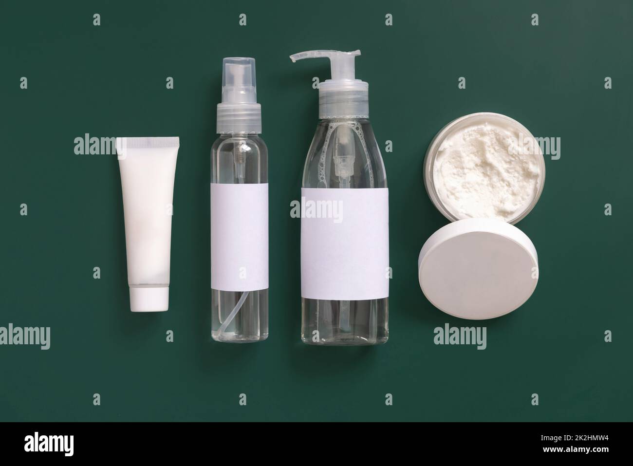 Homemade Cosmetics in plastic tubes and bottles on dark green top view. Brand packaging mockup. Stock Photo