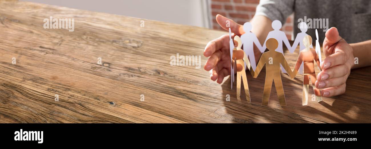 Employee Hands Protecting Cutout Paper People. Equal Human Concept Stock Photo
