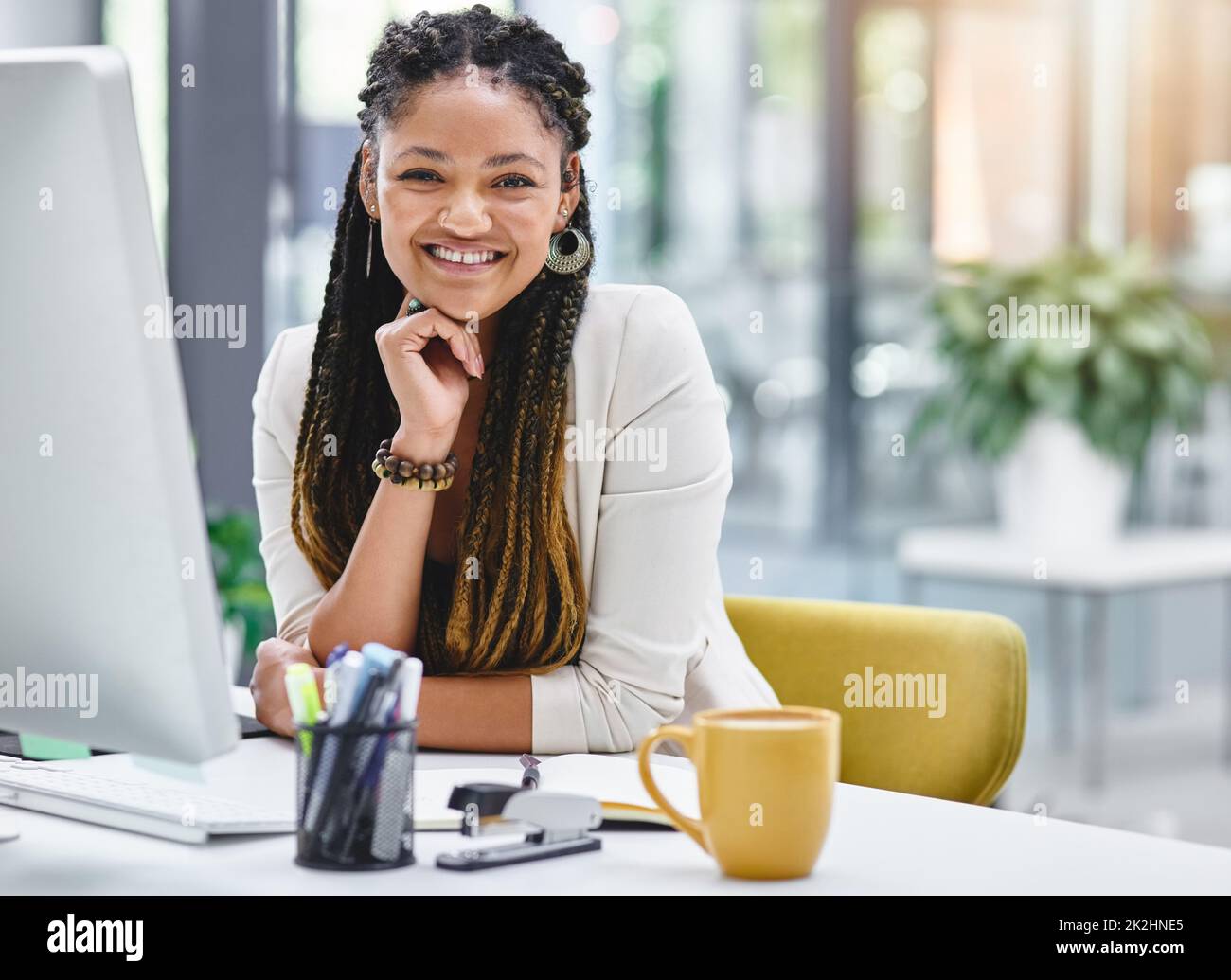 There's nowhere else I'd rather work. Cropped portrait of an attractive young businesswoman sitting at her desk in the office. Stock Photo
