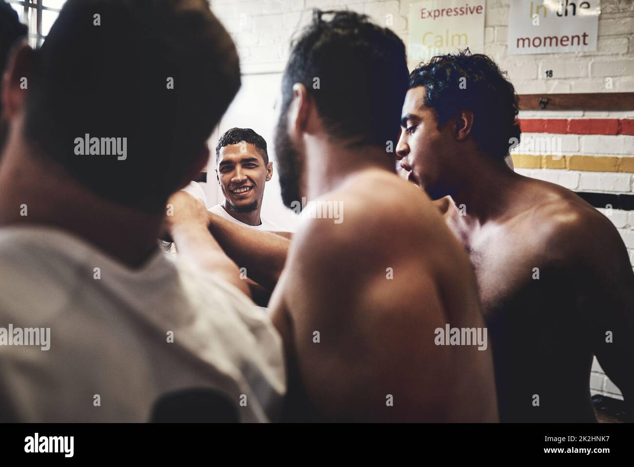 Team spirit is everything. Cropped shot of a group of handsome young rugby players standing together in a huddle in a locker room. Stock Photo