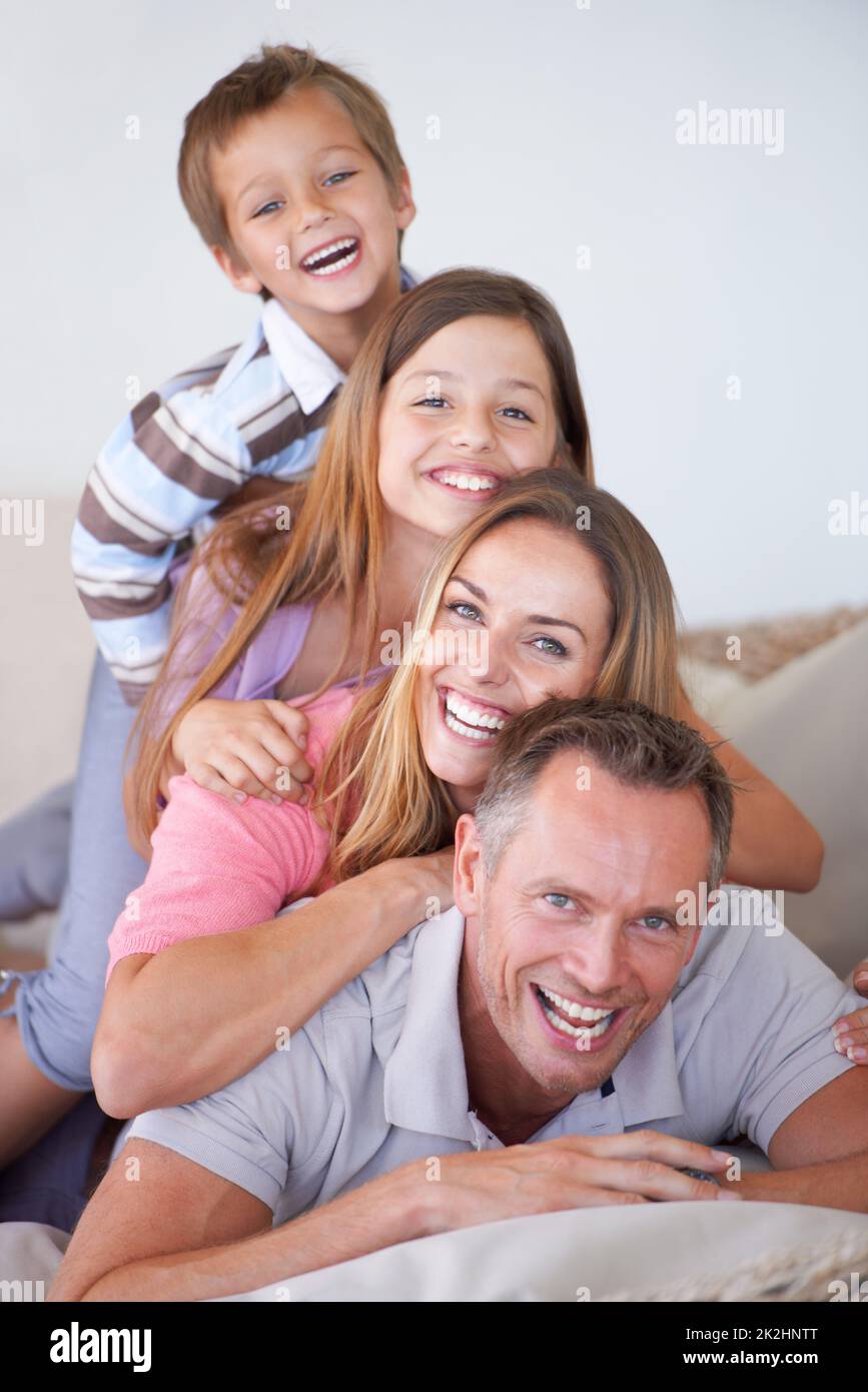 Tiers of management. Portrait of a happy young family of four piled on top of one another. Stock Photo