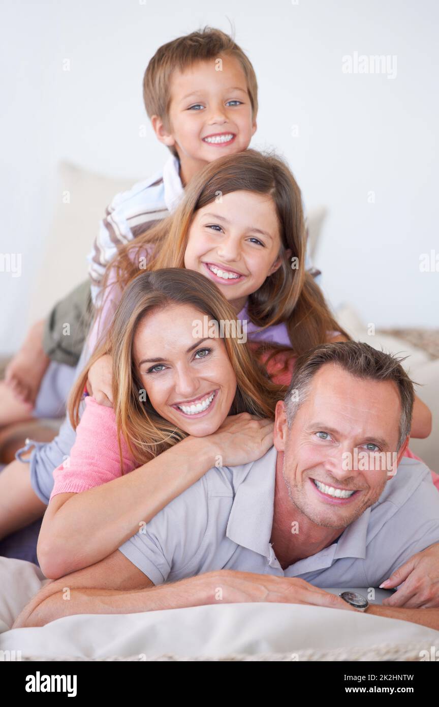 Family is all about balance. Portrait of a happy young family of four piled on top of one another. Stock Photo