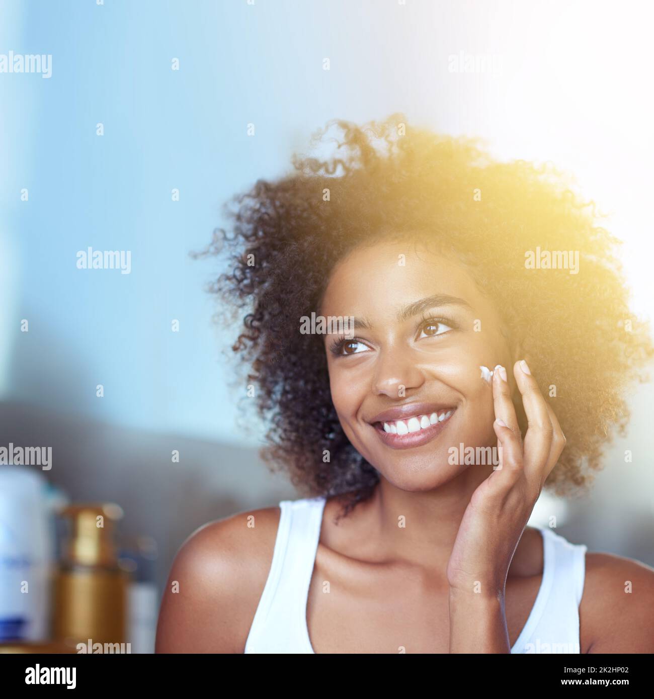She's got a few skincare ideas. Cropped shot of a young woman moisturizing her face in the bathroom. Stock Photo