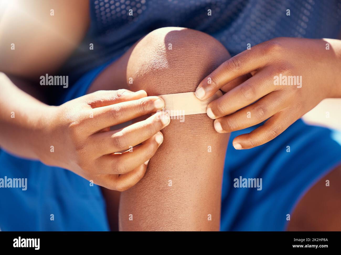 Children, accident and plaster with a band aid on the knee of boy with an injury, wound or pain. Kids, cut and heal with the hands of a male child Stock Photo
