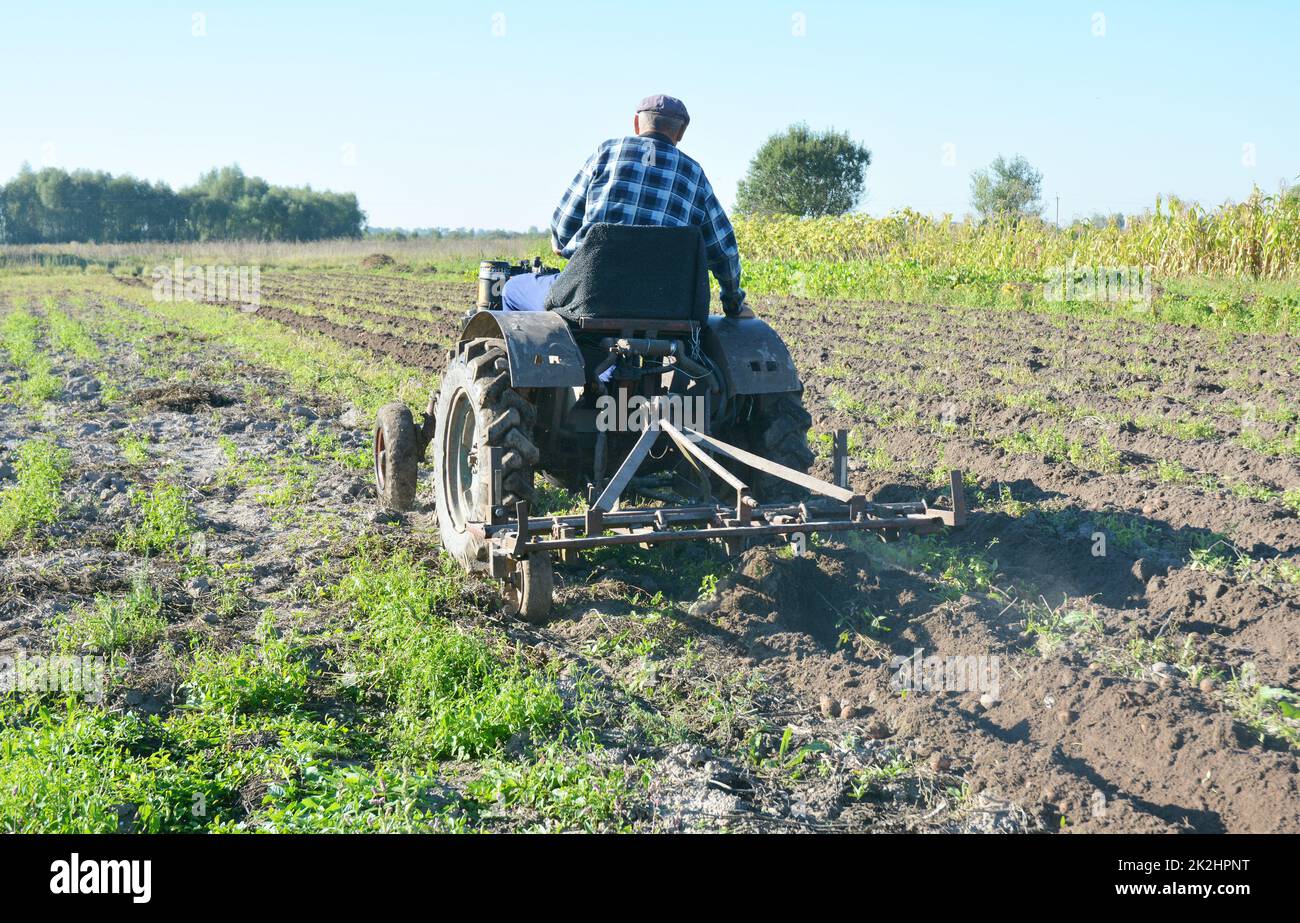 Handmade small tractor plowing field. Old tractor plowing on the farmland. Stock Photo