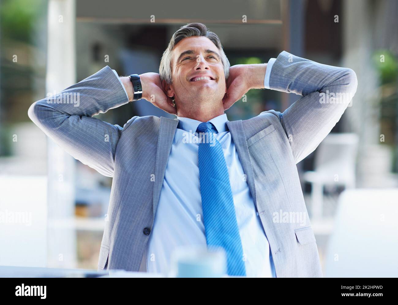 Success has treated him well. a content businessman leaning back in his chair with his hands behind his head. Stock Photo