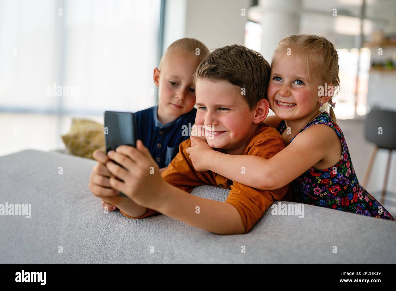 Childhood technology kids smartphone concept. Happy little children playing on mobile phone Stock Photo
