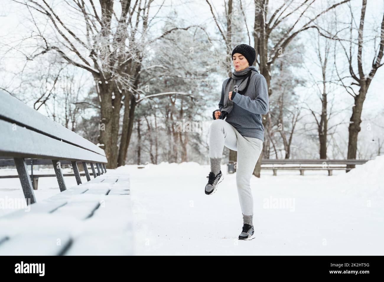 Woman warming up before her jogging workout during winter and snowy day Stock Photo