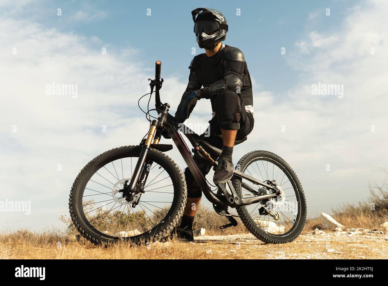 Downhill rider fully equipped with protective gear and his bicycle Stock Photo