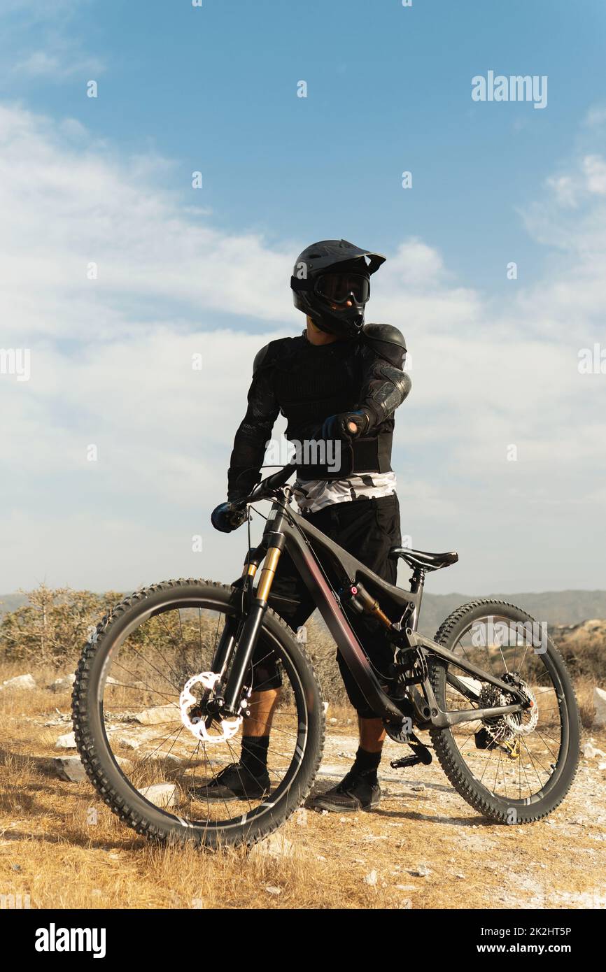 Downhill rider fully equipped with protective gear and his bicycle Stock Photo