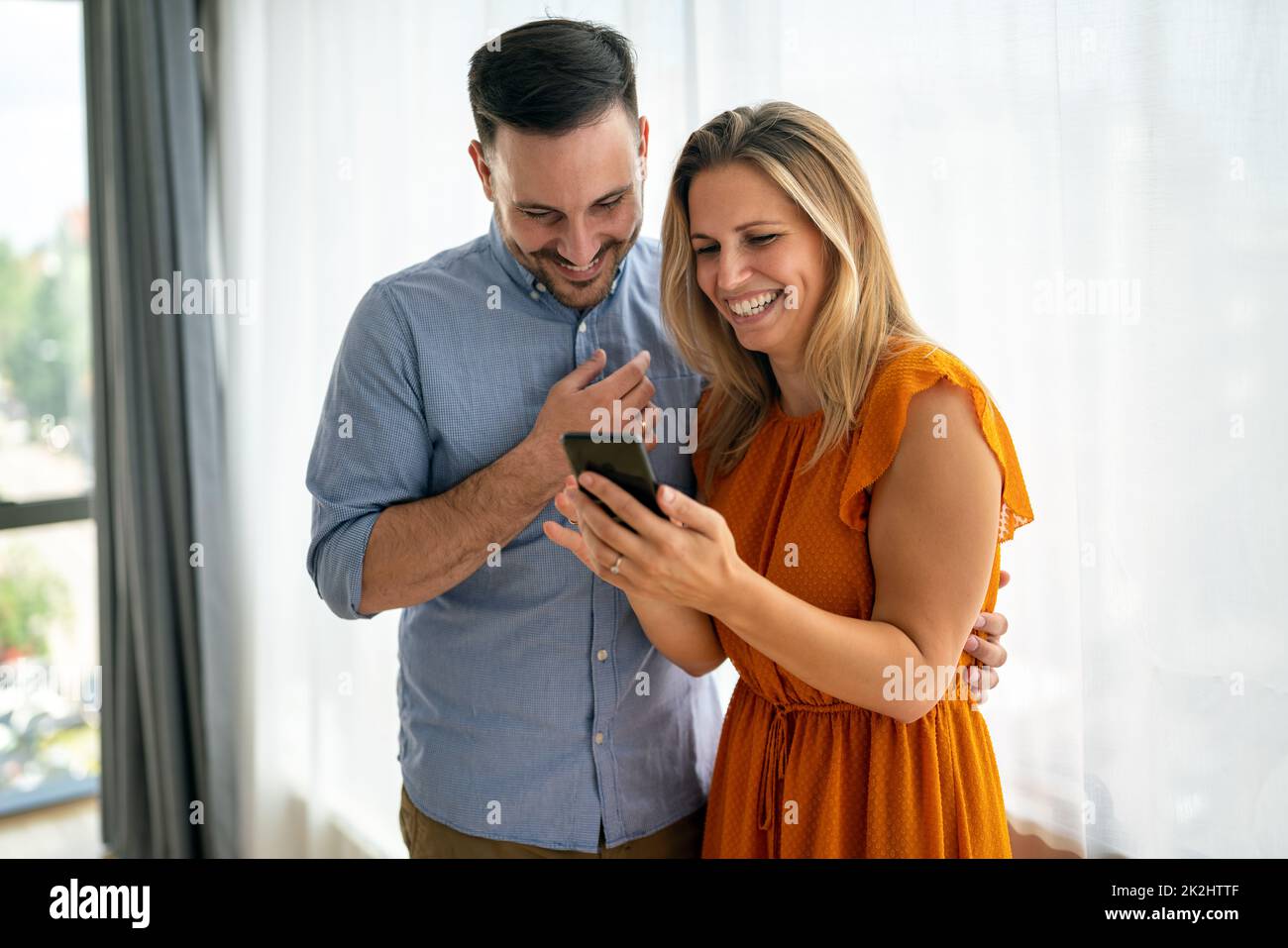 Portrait of happy couple having fun, using smartphone together. People technology concept Stock Photo