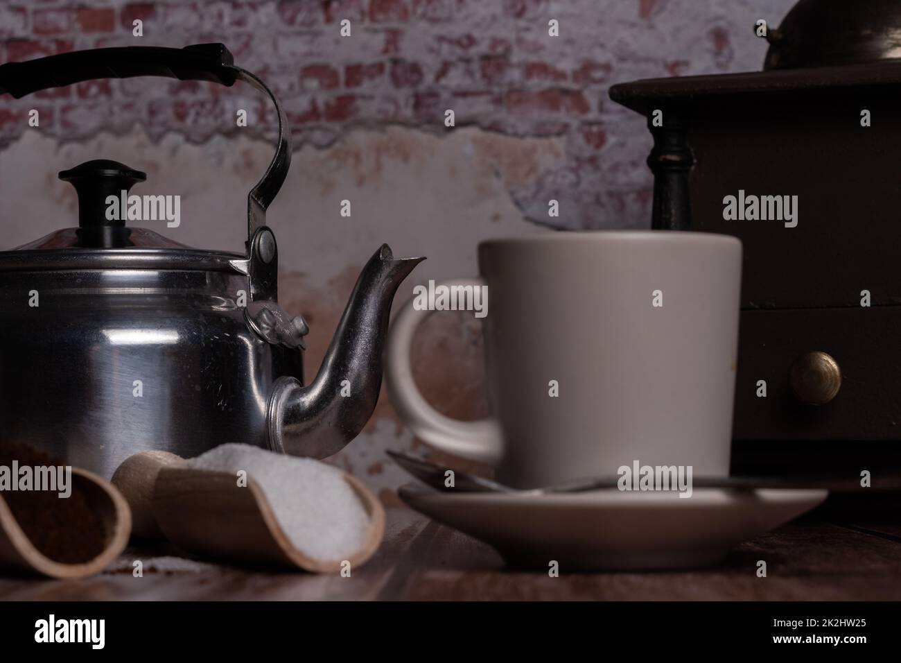 coffee cup with milk jug, coffee grinder and wooden spoons with sugar ground coffee Stock Photo