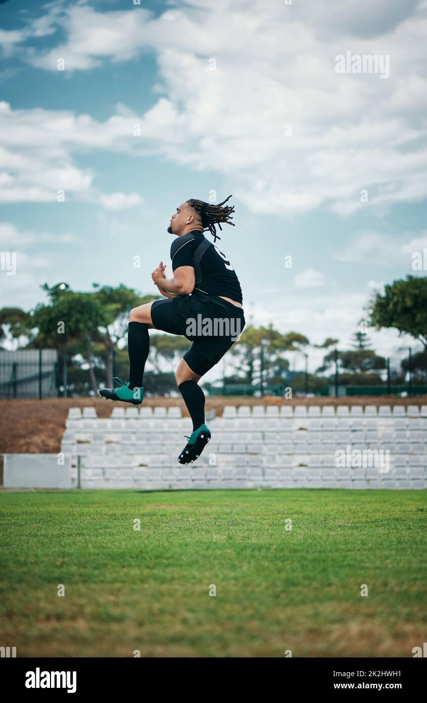 Winning is his thing. Full length shot of a handsome young rugby player jumping into the air while cheering on the field. Stock Photo