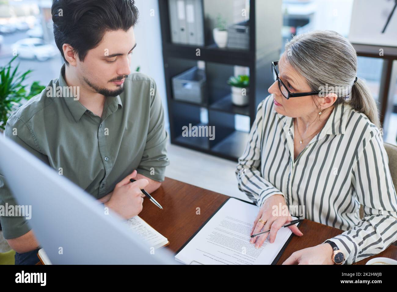 Their plans always work out perfectly. Shot of two businesspeople going through paperwork together in an office. Stock Photo