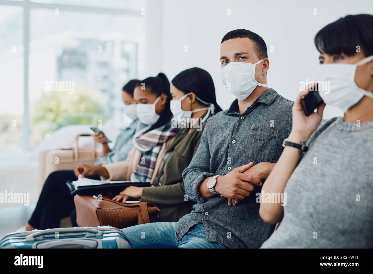 Never underestimate the importance of patience. Shot of a group of young people wearing masks in a waiting room. Stock Photo