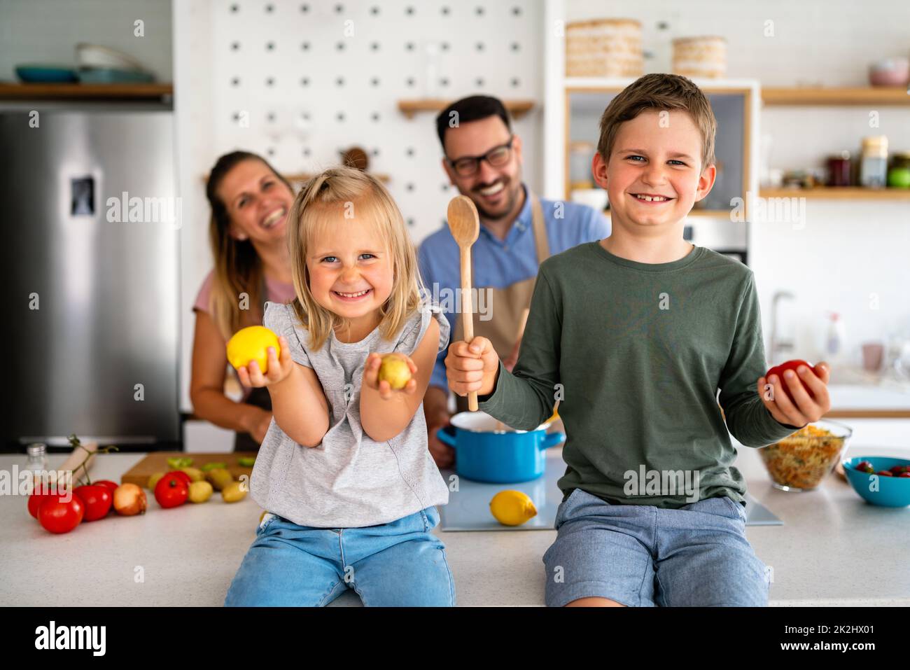 Happy family with children preparing healthy food together in kitchen Stock Photo