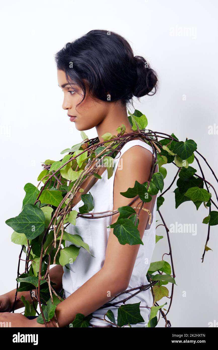 Ivy beauty. Studio shot of an attractive young ethnic woman with foliage over her shoulder. Stock Photo