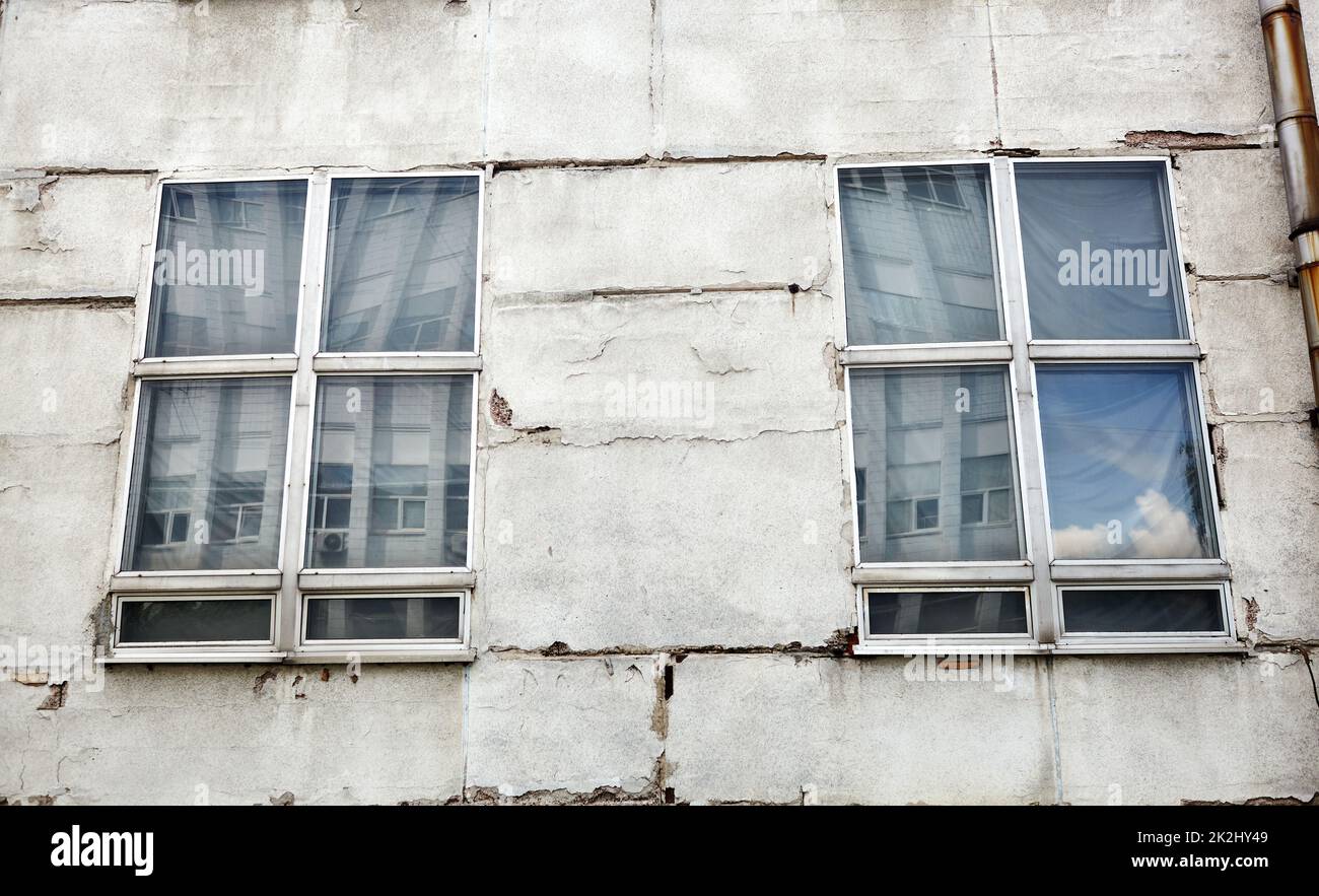 The old concrete wall with windows. Abandoned  facade of factory or industrial building Stock Photo