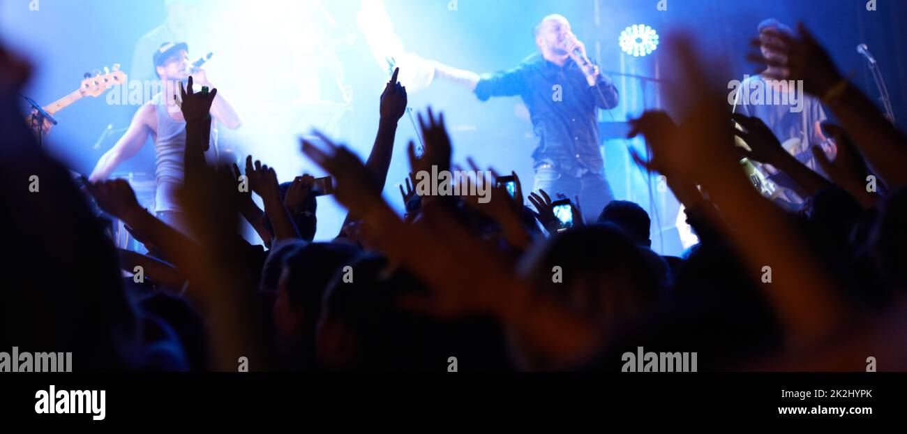 Fans raising their hands. Rearview of an audience with hands raised at a music festival. Stock Photo