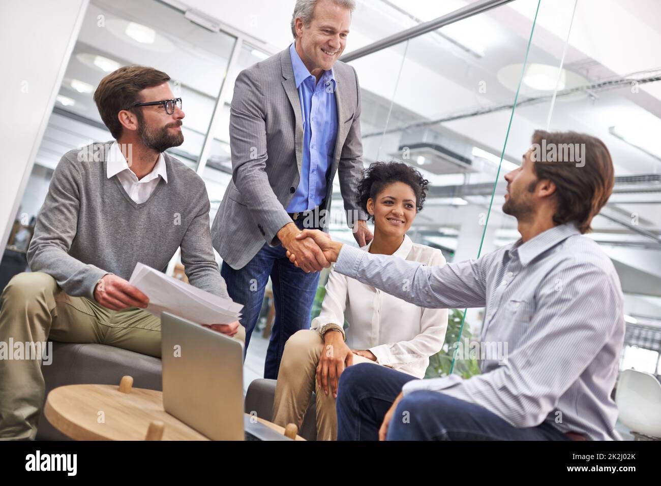You've done well. Shot of a two business professionals shaking hands in an office. Stock Photo