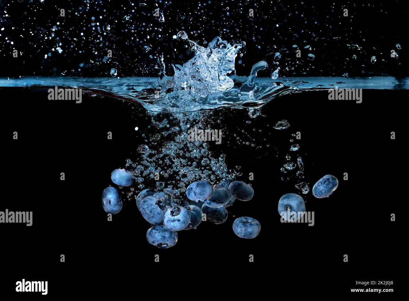 Bunch of fresh ripe blueberries dropped in water with air bubbles and splashes isolated on black background. Stock Photo