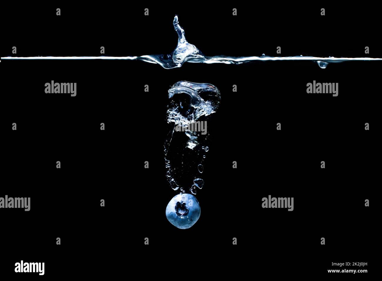 Single blueberry dropped in water with splashes isolated on black background Stock Photo