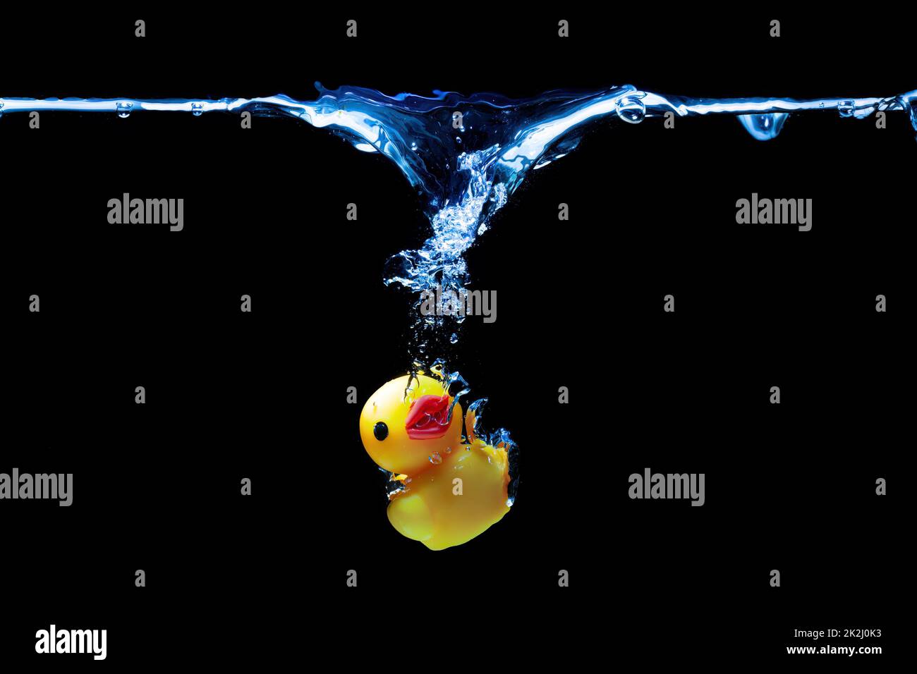 Small yellow toy duck sinking underwater isolated on black background. Stock Photo