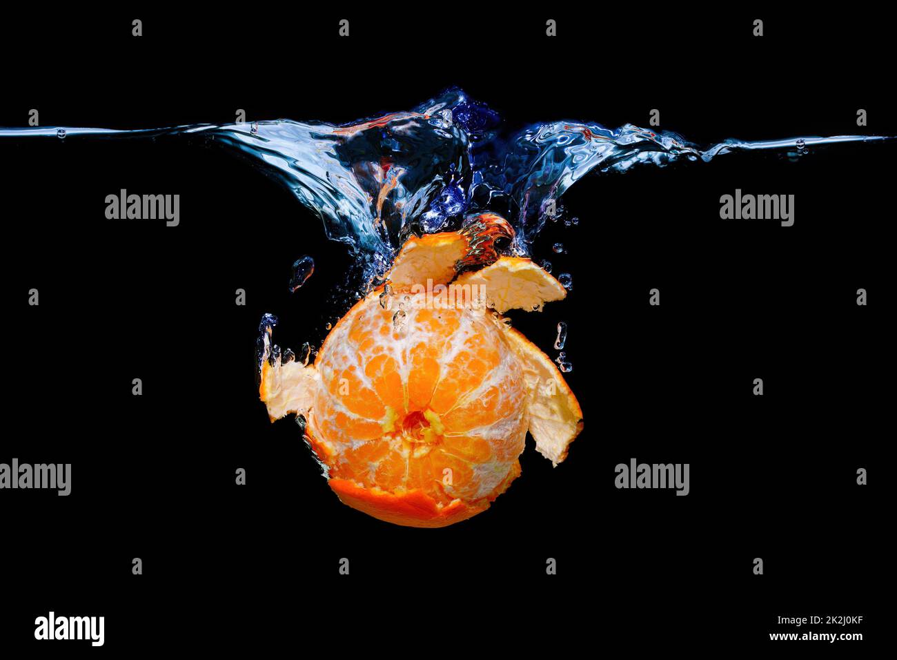 Close-up of a peeled tangerine sinking underwater with splashes isolated on black background. Stock Photo