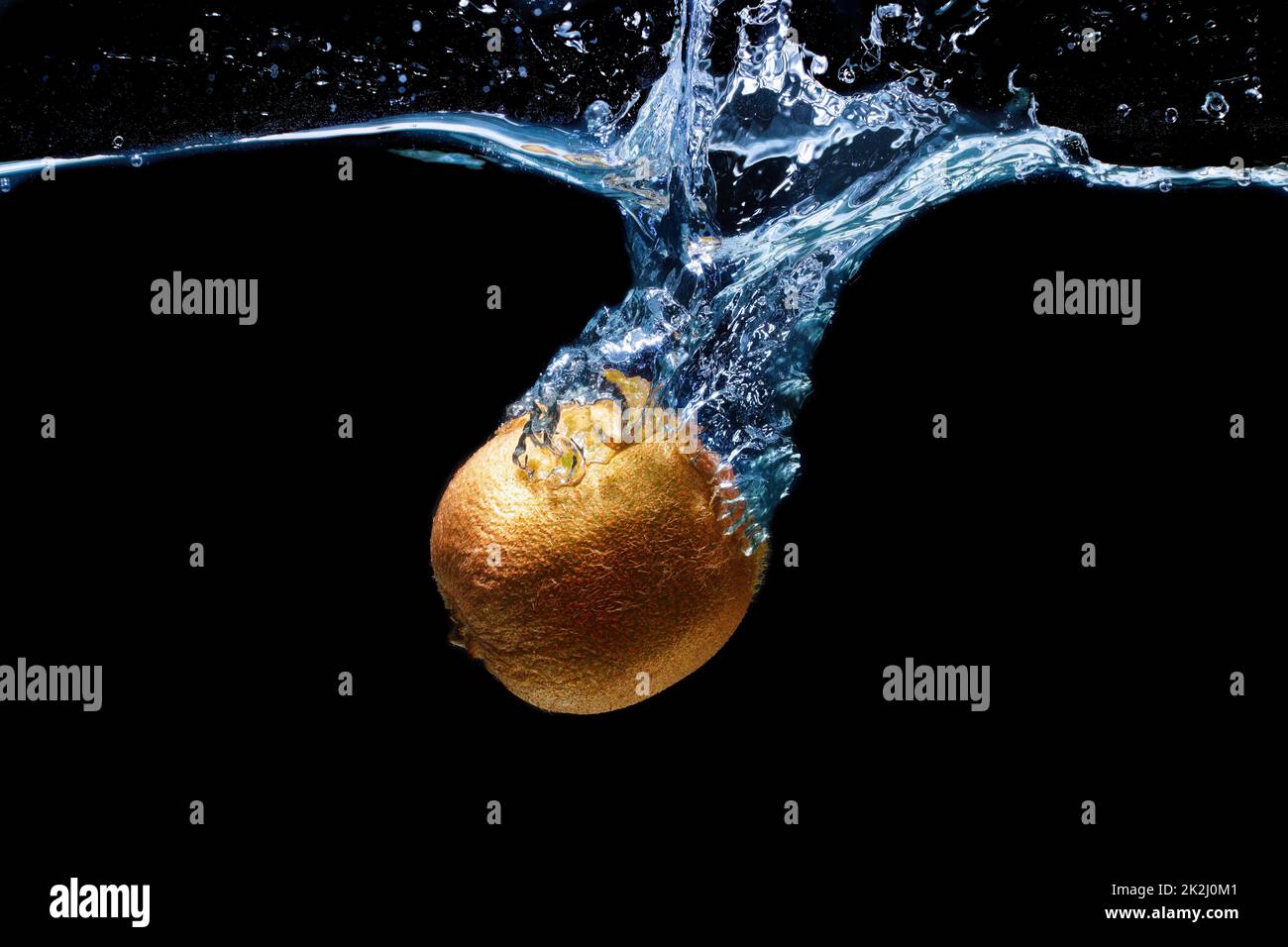 Whole kiwifruit dropped in water with splashes isolated on black background Stock Photo