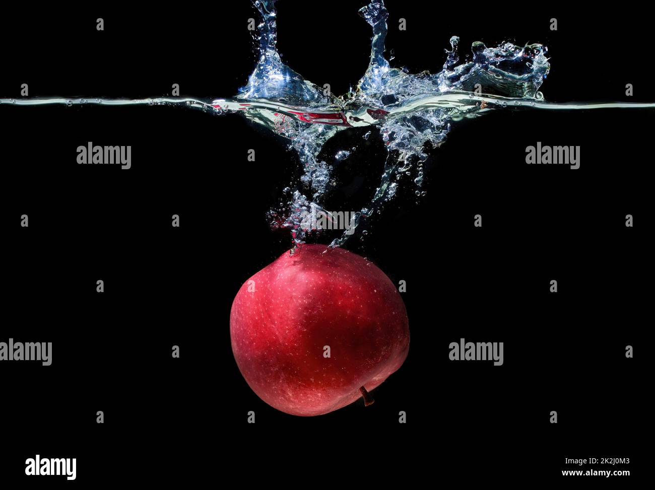 Red apple floating in water with splashes isolated on black background. Stock Photo