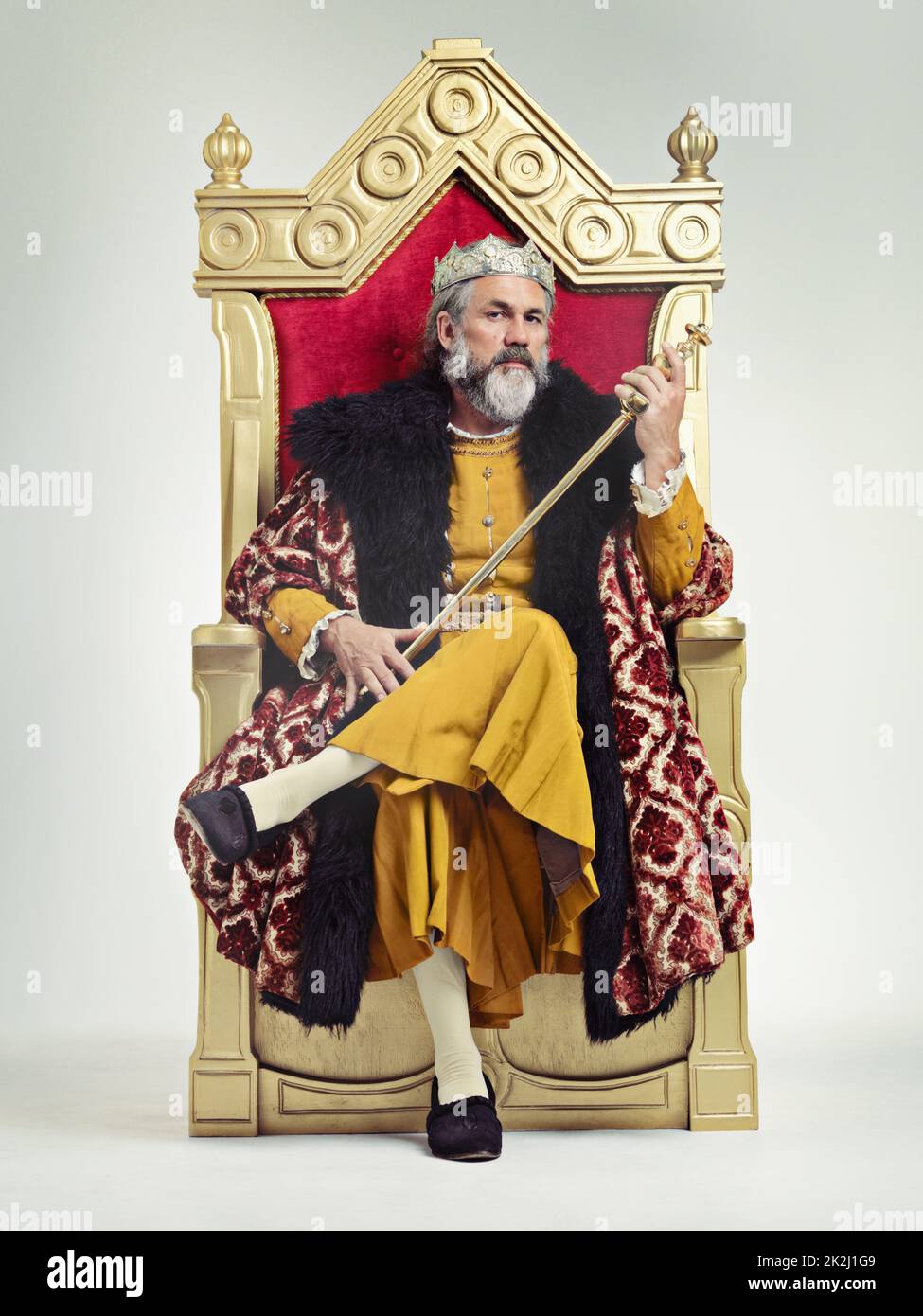 Throne of the kings. Studio shot of a richly garbed king sitting on a throne holding his scepter. Stock Photo