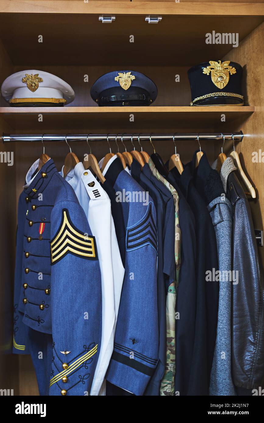 Clothing made for combat. Shot of various military jackets and hats hanging in a closet. Stock Photo