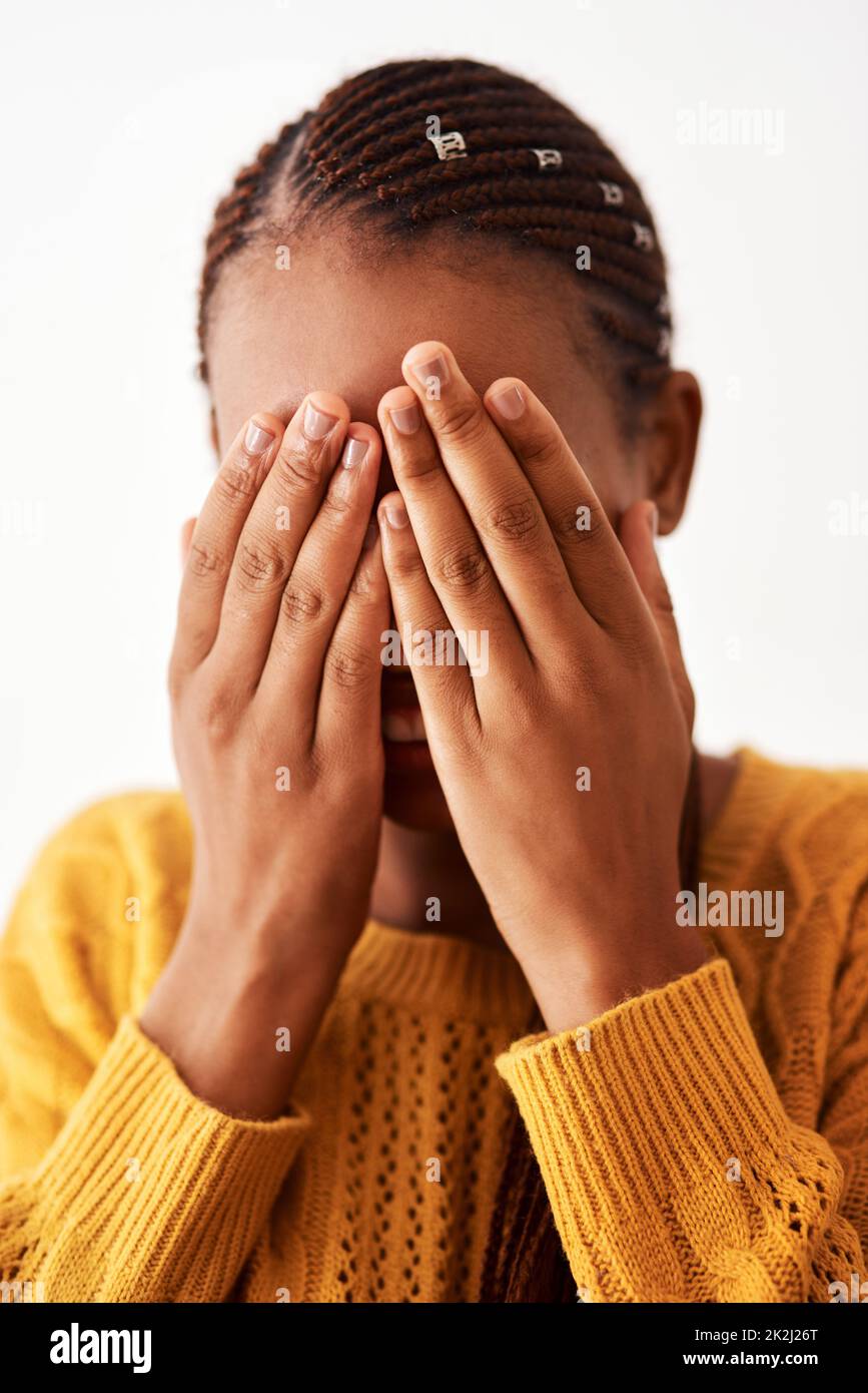 I cant watch. Studio shot of a woman holding her hands over her face while standing against a white background. Stock Photo