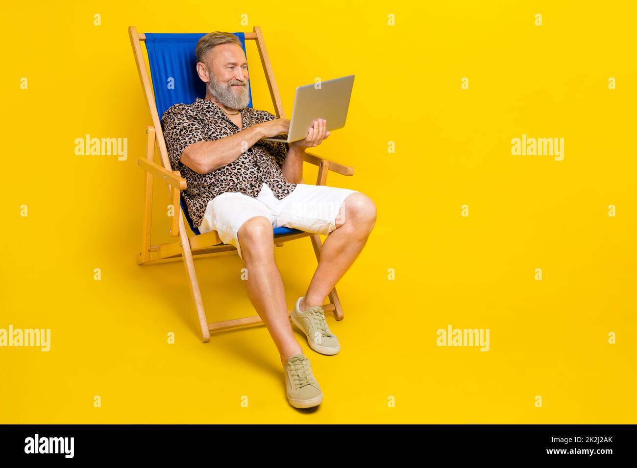 Full body portrait of handsome man sit lounger hold use netbook coworking isolated on yellow color background Stock Photo