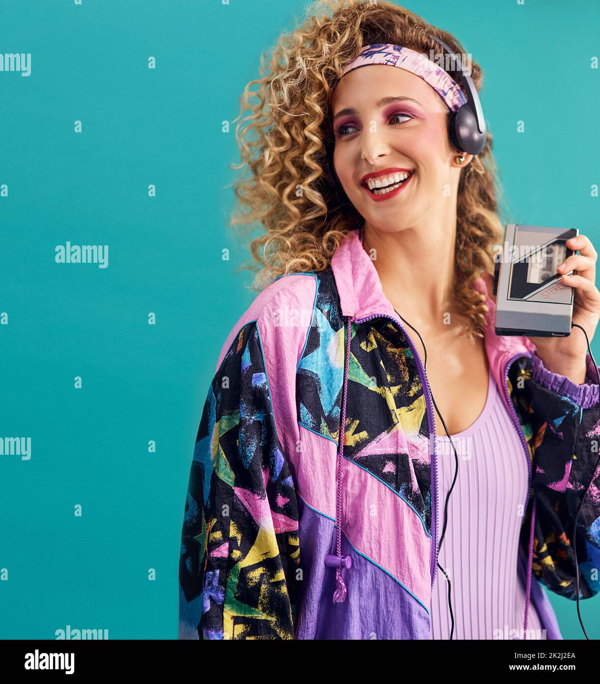 Nothing makes me feel as good as 80s music. Studio shot of a young woman holding a cassette player while dressed in 80s clothing. Stock Photo