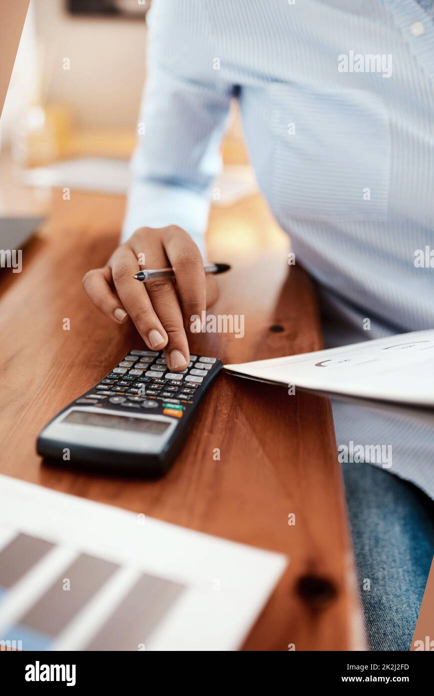 Let the numbers do the talking. Cropped shot of a businesswoman using a calculator while going over financial paperwork at her desk. Stock Photo