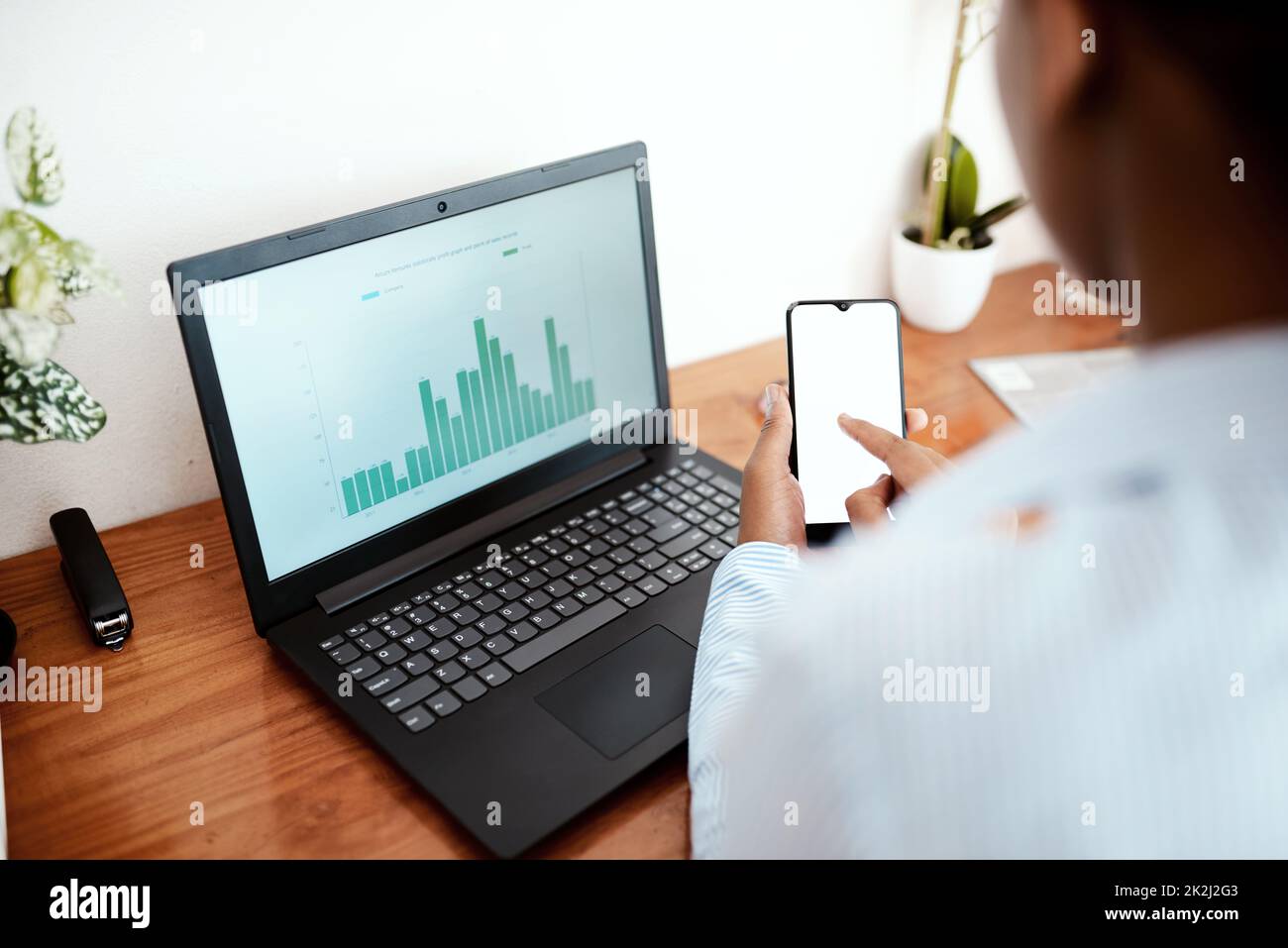 Smart tech is an accountants best friend. Cropped shot of a businesswoman using a laptop and smartphone while analysing financial data at her desk. Stock Photo