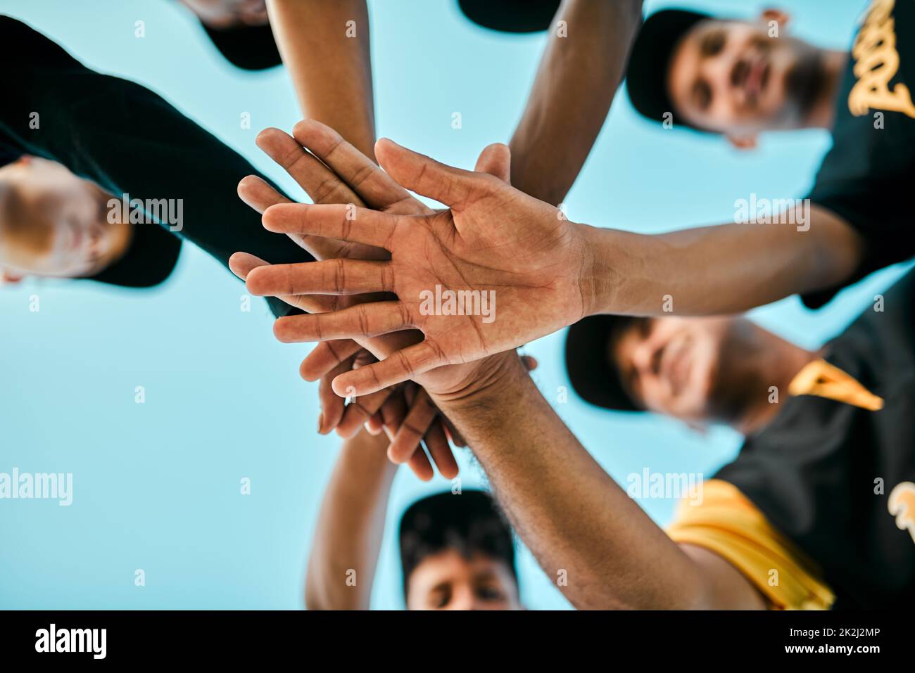 Every player plays a large role. Shot of a team of young baseball players joining their hands together in a huddle during a game. Stock Photo