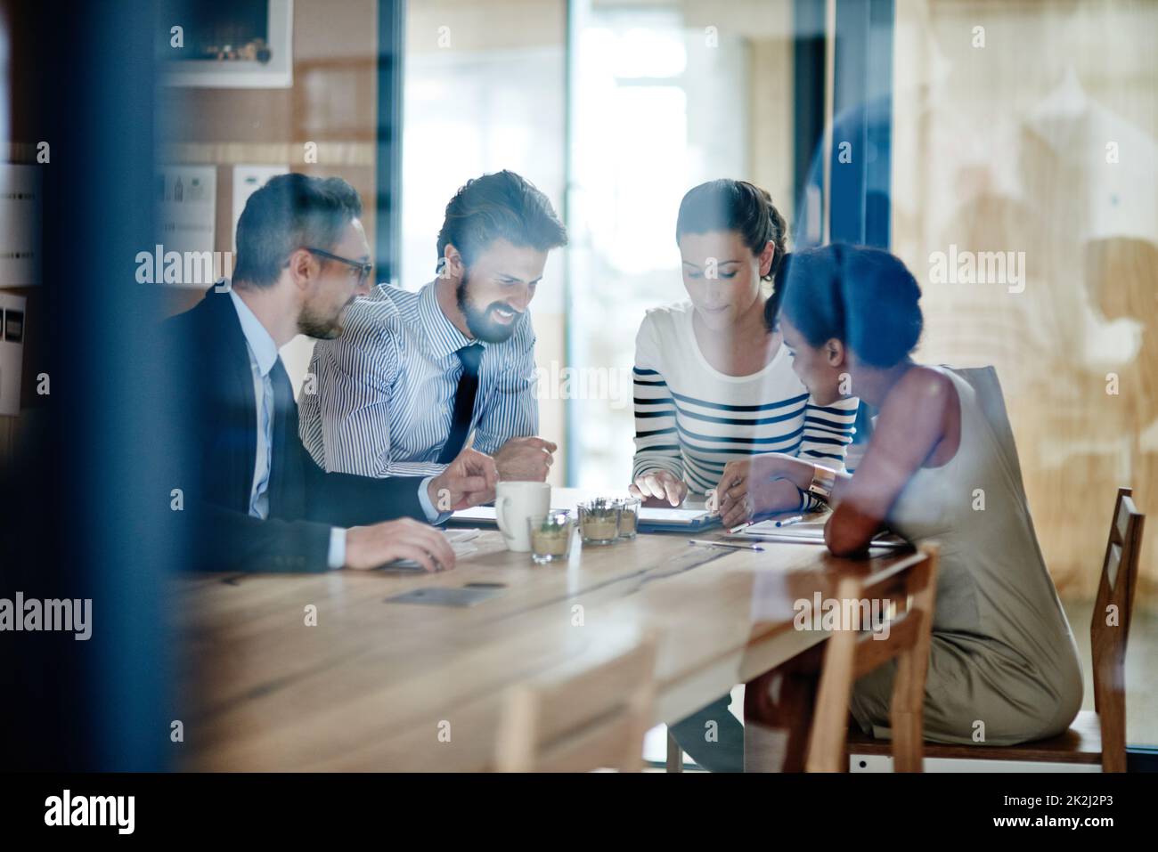 Taking their ideas online. Through the glass shot of a group of colleagues working together in an office. Stock Photo