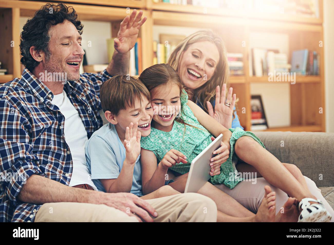 Connecting across borders with smart technology. Shot of a happy family making a video call on their digital tablet together at home. Stock Photo