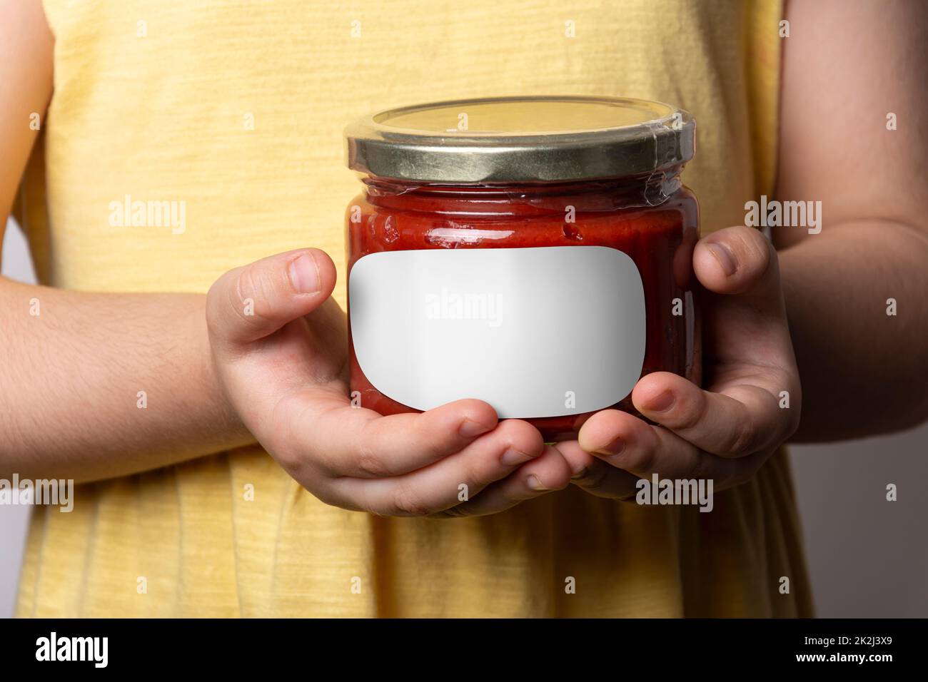 Homemade tomato paste in glass jar in little girl hands mockup series