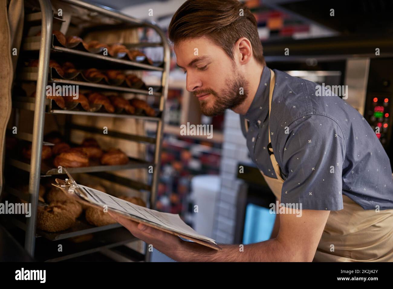 Making sure everything is baked to perfection. Shot of a young business owner counting his baked goods. Stock Photo